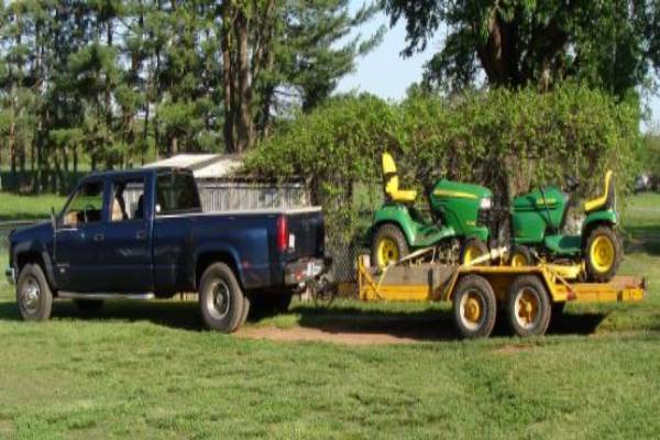 Big Boy Lawn & Gardening team standing in front of a beautifully manicured lawn, wearing green uniforms and smiling