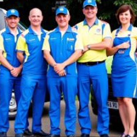 Power Wash team standing in front of their service vehicles, smiling and ready to work